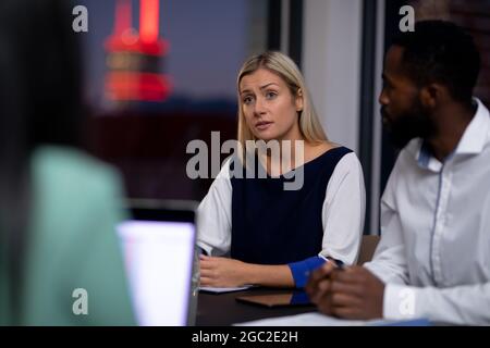 Eine vielfältige Gruppe von Geschäftskollegen, die nachts bei einem Meeting arbeiten Stockfoto