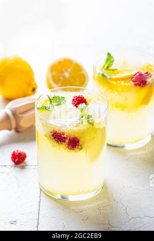 Hausgemachte Limonade mit Minze und Himbeeren in Gläsern, graue Fliesen Hintergrund. Konzept für kalte Sommergetränke. Stockfoto