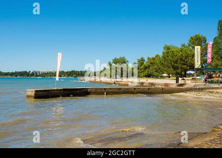 Porec, Kroatien - 10. Juli 2021. Eine Anlegestelle am Parentino Strand außerhalb der historischen mittelalterlichen Küstenstadt Porec in Istrien, Kroatien Stockfoto