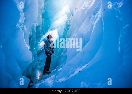 (210806) -- WELLINGTON, 6. August 2021 (Xinhua) -- EIN Wanderführer steht auf dem Grund einer riesigen Eishöhle am Fox Glacier an der Westküste der Südinsel Neuseelands, 27. Juli 2020. Der neuseeländische Fox Glacier ist seit langem eine international bekannte Touristenattraktion. Rob Jewell, CEO von Fox Glacier guiding, ist jedoch zutiefst besorgt über die Stornierungen der Buchung nach der achtwöchigen Pause der Reiseblase Trans-Tasman, die Ende Juli eingeführt wurde, in der Regel die goldene Saison für Unternehmen der Gemeinde Fox Glacier, einem abgelegenen und kleinen Ausflugsziel in Neuseeland. ZU „F“ Stockfoto