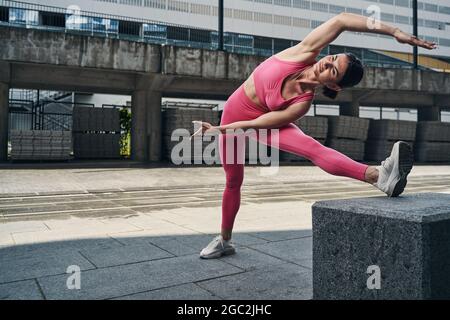 Frau macht Seitenstrecken auf der Stadtstraße Stockfoto