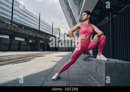 Weibchen streckt das rechte Bein, während sie sich auf einen Steinblock lehnt Stockfoto
