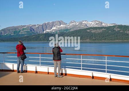 Glacier Bay National Park, Alaska; Juli 2021. Passagiere stehen an der Schiene eines großen Kreuzfahrtschiffs, wenn es in den Glacier Bay National Park, Alaska, einfährt. Stockfoto