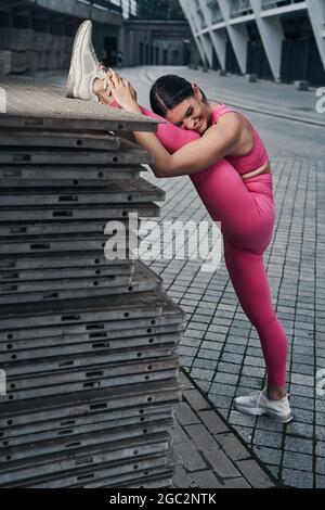 Trainieren einer Frau, die den Kopf auf ihr Bein legt und lacht Stockfoto