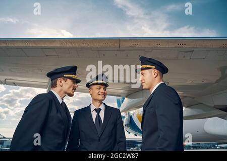 Drei Flieger, die sich mit einem gelandeten Jetliner unterhalten Stockfoto