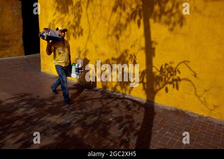 Straßenhändler, die am Boca del Puente und dem Uhrturm-Denkmal am Haupteingang der alten ummauerten Stadt Cartagena, Kolumbien, vorbei kommen. Stockfoto