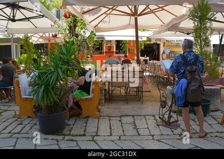 Porec, Kroatien - 10. Juli 2021. Ein Tourist schaut sich ein Menü außerhalb eines Restaurants im historischen Zentrum der mittelalterlichen Küstenstadt Porec in Istrien an Stockfoto