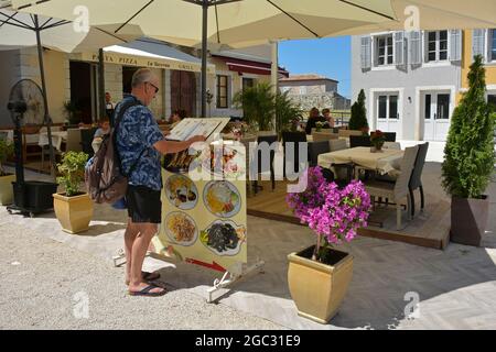 Porec, Kroatien - 10. Juli 2021. Ein Tourist schaut sich ein Menü außerhalb eines Restaurants im historischen Zentrum der mittelalterlichen Küstenstadt Porec in Istrien an Stockfoto