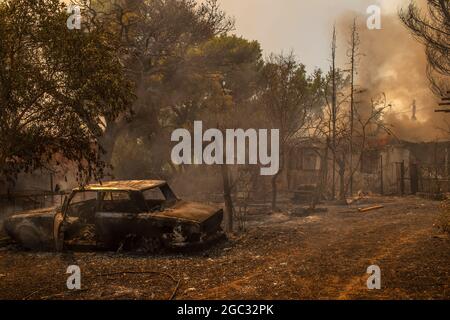 Krioneri, Griechenland. August 2021. Ein ausgebranntes Auto steht im Hinterhof eines Hauses während eines Waldbrands nördlich von Athen. Seit den frühen Morgenstunden am Freitag wurden die zahlreichen Brände durch starke Westwinde weiter anheizen. Quelle: Angelos Tzortzinis/DPA/dpa/Alamy Live News Stockfoto