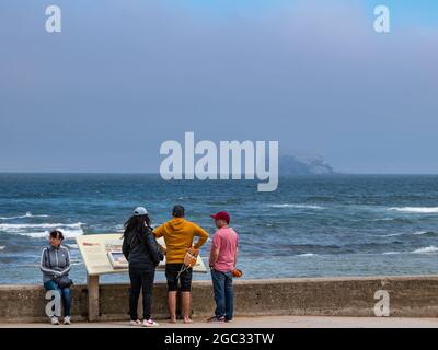 North Berwick, East Lothian, Schottland, Großbritannien, 6. August 2021. Wetter in Großbritannien: Nebliger Tag vor starkem Regen: Die Stadt ist von Meeresnebel umgeben, während die Menschen entlang der Promenade spazieren. Im Bild: Der Bass Rock ist fast unsichtbar über den Firth of Forth von Milsey Bay Stockfoto