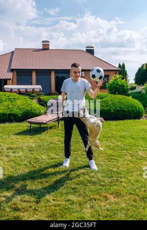 Mann mit ampuiertem Arm und Prothese, der im Hinterhof mit seinem Hund spielt Stockfoto