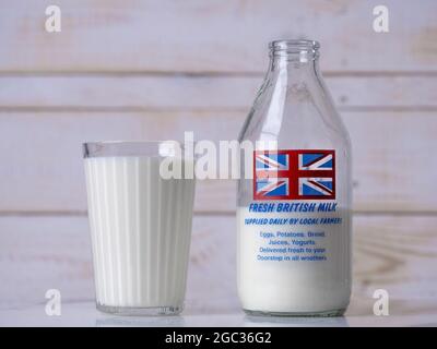 Ein Glas Milch neben einer traditionellen britischen Glasmilchflasche mit Union Jack Flag-Design. Stockfoto