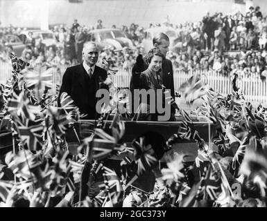 Die Königliche Tour die Königin und der Herzog, umgeben von einer Masse von Kindern, die Flaggen schwenken, als sie während der Abschlussphase ihrer Neuseelandtour an einem Kinderpicknick auf dem Forbury Park-Rennkurs in Dunedin teilnahmen. Februar 1954 Stockfoto