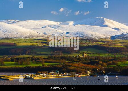 Bangor Port und Penrhyn Castle von der Menai Strait aus mit Schnee auf den Bergen von Snowdonia im Winter von der Menai Bridge aus gesehen Gwynedd Wales UK Stockfoto