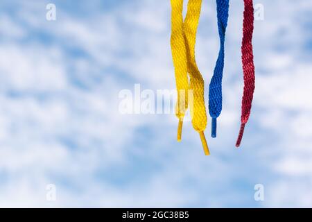 Flagge Kolumbiens mit Schnürsenkeln, die auf einem Hintergrund des Himmels und der Wolken hängen Stockfoto