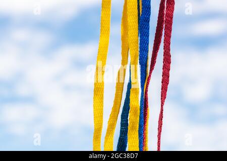 Flagge Kolumbiens mit Schnürsenkeln, die auf einem Hintergrund des Himmels und der Wolken hängen Stockfoto