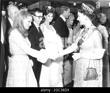 Die britische Königin Elizabeth II schüttelt sich die Hände mit der Schauspielerin Ursula Andress, Woody Allen und Raquel Welch schauen sich an, bevor der Film Born Free von Royal Film Preforemance 1966 am Odeon Theatre in Leicester Square, London, beginnt. März 1966. Stockfoto