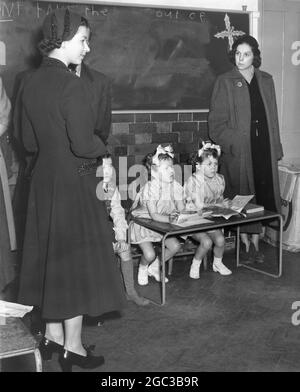 Die Queen Elizabeth II schaut in das Kinderzimmer der Lansdowne Road School Tilbury Essex die Schule wird als Flüchtlingszentrum für Flutopfer genutzt die Zwillinge sind lokale Kinder, die im Februar 1953 als Henry Twins bekannt sind Stockfoto