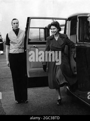 Die Königin Elizabeth II lächelt, als sie bei der Ankunft in Lee auf dem Solent Airfield aus dem königlichen Auto tritt, um die Fliege vorbeifliegen zu sehen.Halten Sie die Tür offen führt den Wren J Simms Women's Royal Naval Service of Windsor 21 November 1952 Stockfoto