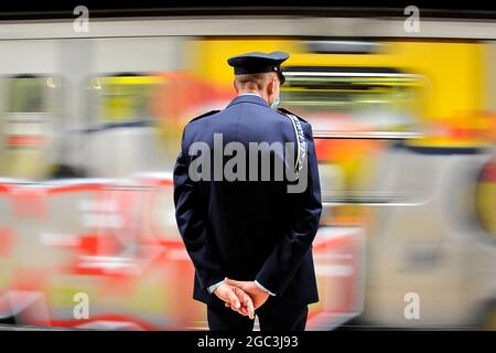 Napoli, Italien. August 2021. Polizeibeamter von hinten beobachtet einen Zugpass, während der Einweihung des Bahnhofs Piazza Duomo in Neapel. Neapel, Italien, 06. August 2021. (Foto von Vincenzo Izzo/Sipa USA) Quelle: SIPA USA/Alamy Live News Stockfoto