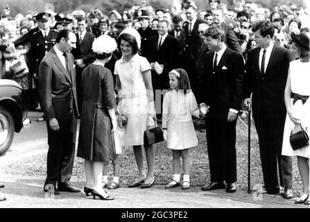 Jacqueline Kennedy begrüßt Königin Elizabeth II. Bei der Ankunft in Runnymede, Surrey. Mit Frau Kennedy sind ihre beiden Kinder Caroline (7) und John (4) . Die Königin enthüllt das Denkmal in Runnymede dem Ehemann von Frau Kennedy, dem verstorbenen US-Präsidenten John F. Kennedy. Ebenfalls anwesend sein wird der Bruder des verstorbenen Präsidenten, die Senatoren Edward und Robert Kennedy. 14 May 1965 Lord Harlech auf der linken Seite Stockfoto