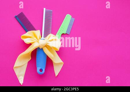 Drei Arten von Friseurscheren mit einer gelben Schleife auf einem rosa Hintergrund. Draufsicht, Layout, Kopierbereich. Stockfoto