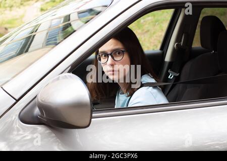 Nahaufnahme einer jungen Fahrerin. Mädchen lernt, ein Auto zu fahren. Angst vor dem Verkehr, Staus. Stress beim Autofahren. Stockfoto