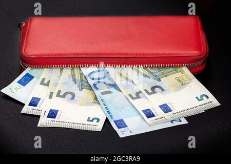 Nahaufnahme von Euro-Banknoten-Bündeln und Öffnung einer roten Brieftasche auf dunklem Hintergrund. Selektiver Fokus. Stockfoto