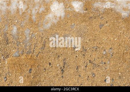 Hintergrund Eis im Sand, Eis Stalaktiten Raureif im Sand. Eiskristalle auf dem gelben Sand. Blick von oben. Multitasking-Hintergrund Stockfoto