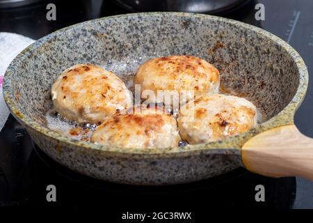 Der Prozess des Kochens in einer Pfanne mit gebratenem Fleisch, Fleischbällchen, Grill. Fast Food-Konzept - Nahaufnahme von Koteletten. Stockfoto