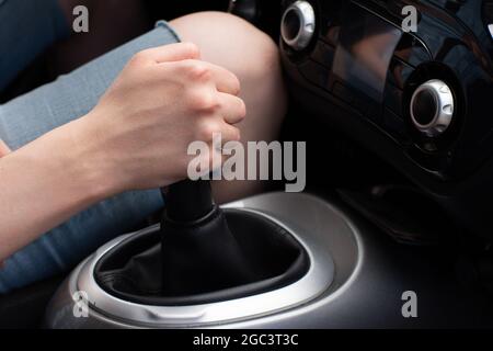 Nahaufnahme einer weiblichen Hand, die ein manuelles oder automatisches Getriebe von der Parkstellung auf die Fahrt umstellt, selektiver Fokus. Stockfoto