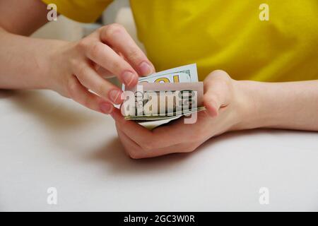 Weibliche Hände, die eine Packung Dollar auf einem Lichtständer drehen, das Konzept der finanziellen Unabhängigkeit. Stockfoto