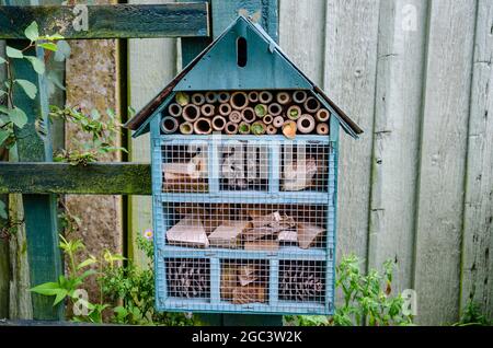Ein Bienen- oder Insektenhotel, das an einen Pfosten in einem Garten angeschlossen ist, um Insekten einen sicheren Ort zum Winterschlaf zu bieten. Stockfoto