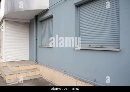 Weiße Jalousien an der Tür und graue Fenster als Schließung des Ladens. Retail Crisis Concept. Geschlossene Geschäfte aufgrund von Coronavirus COVID19. Stockfoto