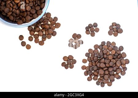 Trockenes Tierfutter für Hunde und Katzen in einer Schale und etwas locker, in Form einer Pfote auf weißem Hintergrund Draufsicht nachgestellt, flach liegend. Platz für Text Stockfoto