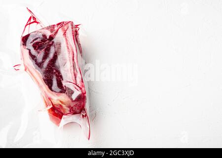 Frisches, marmoriertes Fleisch, schwarzes angus-Steak im Vakuum-Plastikbeutel für Sous-Vide-Set, auf weißer Steinoberfläche, mit Platz für Text Stockfoto