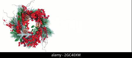 Langes Banner mit einem traditionellen Weihnachtskranz in roten Tönen auf weißem Hintergrund mit Kopierfläche. Schöner Kranz mit Stechbeeren für festliche ne Stockfoto