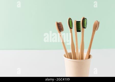 Umweltfreundliche Bambus-Zahnbürsten über der grünen Wand. Konzept für Abfallfreie Hygieneprodukte. Zahnpflegegeräte. Stockfoto