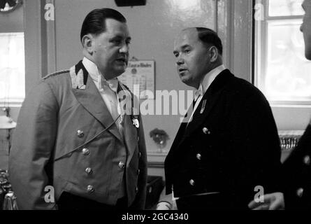 Hinter den Kulissen bei einem Staatsbankett. Bankett für Königin Elizabeth II. Im Mansion House, London nach ihrer Commonwealth Tour im Jahr 1954. Die Catering-Firma von Ring & Brymer (Birch's) Ltd hat die Verpflegung bei jedem Krönungsbankett der Corporation of London seit der Krönung von Königin Victoria übernommen und hat mehr gekrönte Köpfe als jedes andere Unternehmen auf der Welt betreut. 19. Mai 1954 Fotoshows: Zwei ganz besondere Diener warten auf das Wort. Auf der linken Seite ist der persönliche Fußmann des Duke of Edinburgh zu sehen. Auf der rechten Seite ist die Seite der Königin – er dient am Tisch und geht mit ihrer Majestät Stockfoto