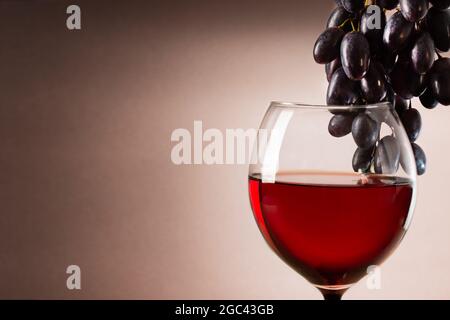 Ein Glas Rotwein und rote Traube. Weinkomposition mit Kopierraum für Design. Stillleben von Wein und Traube. Stockfoto