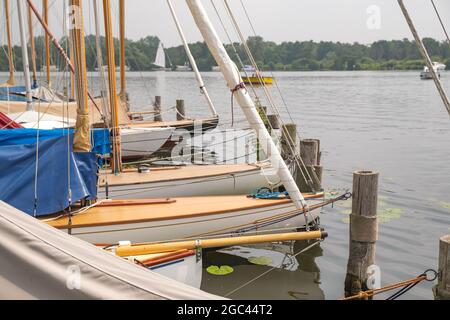 Wroxham, Norfolk Broads, Großbritannien – Juli 2021. Während der jährlichen Segelregatta festten Segelboote entlang der hölzernen Bühne an der Seite von Wroxham Broad Stockfoto