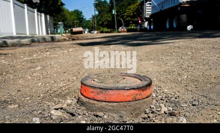 Blick auf die Straße vom Straßenbau mit orangefarbener Markierung auf dem Schlot der Rohrleitung Stockfoto
