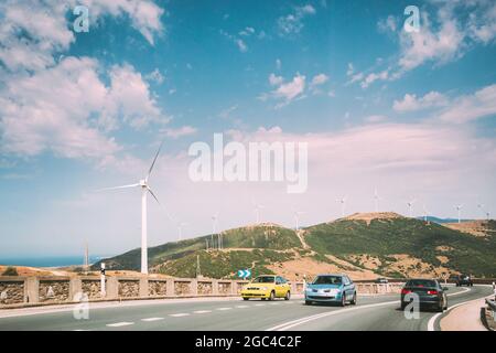 Autos Bewegung von Fahrzeugen auf der Autobahn, Autobahn vor dem Hintergrund von Windmühlen, Windturbinen für die Stromproduktion. Stockfoto