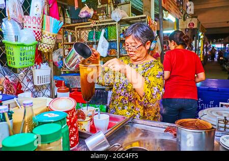 LAMPANG, THAILAND - 8. MAI 2019: Der Händler von Tiny Stall auf dem Ratsada-Markt bereitet traditionellen thailändischen Eiskaffee mit gesüßter Kondensmilch zu Stockfoto