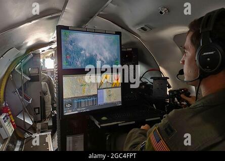 Capt. Alex McArdel, Offizier des 141st Air Betanking Wing RC-26B Aircraft Mission Systems, nutzt die Kamera des Flugzeugs, um Wildlandbrände in der nordwestlichen Region der Vereinigten Staaten zu kartieren und zu erkennen, 1. August 2021. Der RC-26 ist mit der Nutzung seiner hochmobilen Plattform beauftragt, indem er Infrarotbilder und Videoaufnahmen der Brände von oben erstellt, um Wildlandbrände und Hotspots in der westlichen Region der Vereinigten Staaten zu kartieren und zu erkennen. Die RC-26-Besatzungen können Hotspots aus bis zu 60 Seemeilen Entfernung erkennen, bevor sie zu Bränden werden, und helfen Teams, diese Orte zu erreichen. First Air Force (Air Forces No Stockfoto