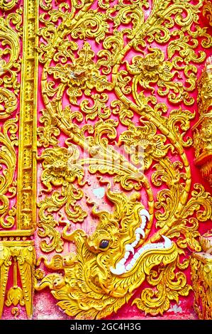 Die Außenwand des Wat Phrao Tempels ist mit einem Relief der Naga-Schlange und feinen Blumenmustern, Wat Phra That Lampang Luang, Lampang, Thailand, geschmückt Stockfoto