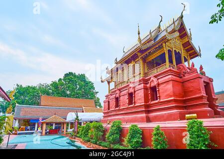 Die malerische rote Ho Trai Buddhistische Bibliothek, die heilige Manuskripte enthält, Wat Phra That Hariphunchai Tempel, Lamphun, Thailand Stockfoto