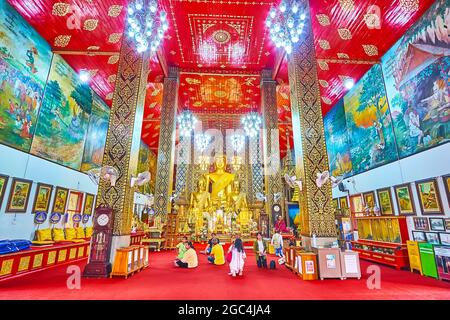 LAMHPUN, THAILAND - 8. MAI 2019: Innenraum des Viharn Luang des Wat Phra That Hariphunchai Tempels mit goldenen Buddha-Bildern, Wandmalereien, feinen Mustern und wo Stockfoto