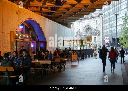 London, Großbritannien, 6. August 2021: Am Freitagabend auf der Londoner South Bank haben Trinker Zeit für ein Pint und ein wenig Geselligkeit am Waterloo Tap, wobei die Waterloo Station im Hintergrund bereit ist, Trinker sicher mit öffentlichen Verkehrsmitteln nach Hause zu bringen. Obwohl die Besucherfrequenz nicht so hoch ist wie in Zeiten vor der Pandemie, herrscht immer noch eine gute Stimmung am Freitagabend, da sich die Menschen auf das Wochenende freuen. Anna Watson/Alamy Live News Stockfoto