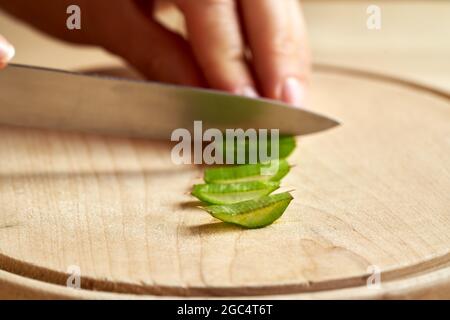 Scheiben Aloe Vera Blätter, mit einem Messer und Hand im Hintergrund Stockfoto